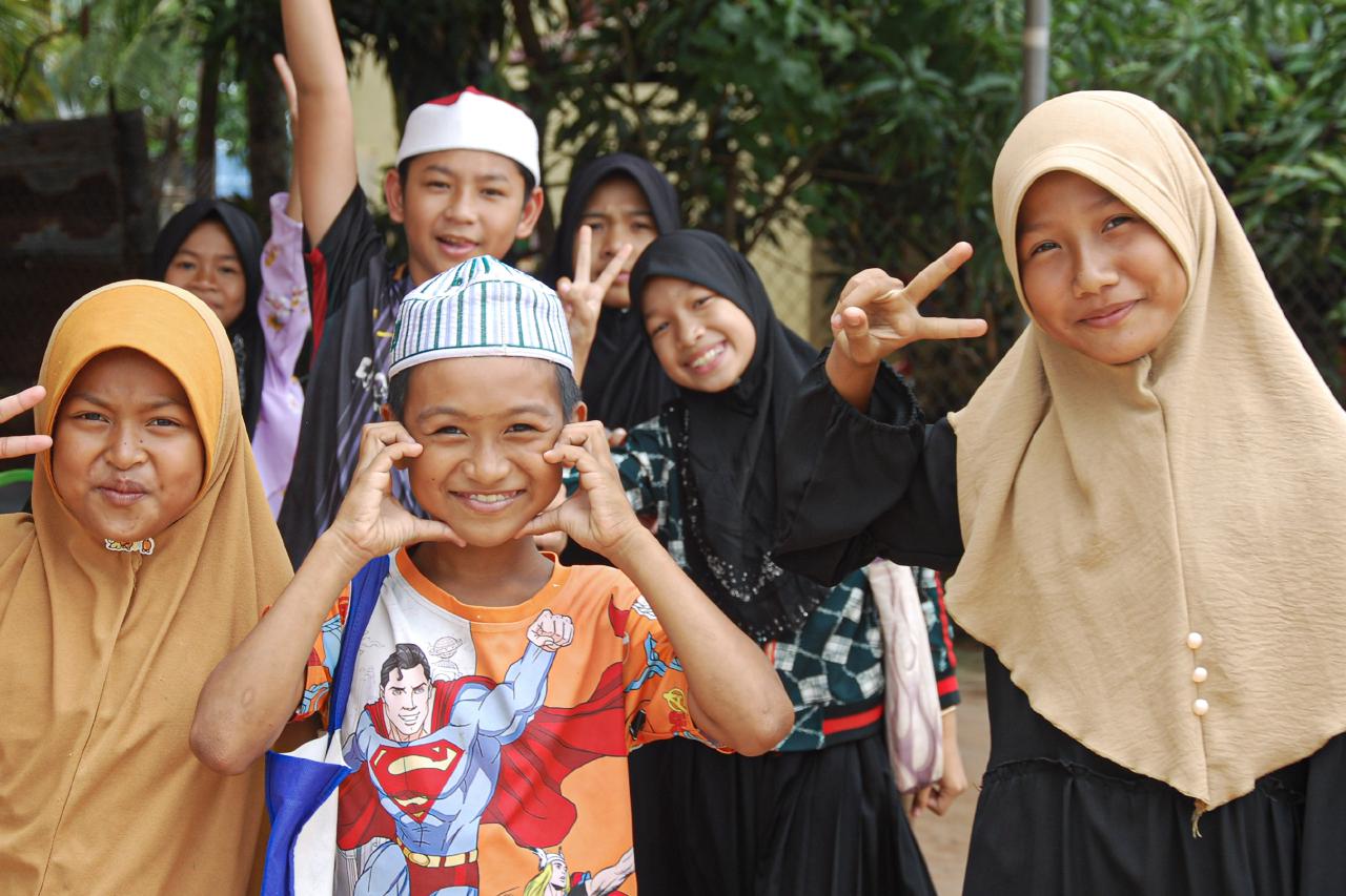 Children cycling past rice fields in rural Kampot