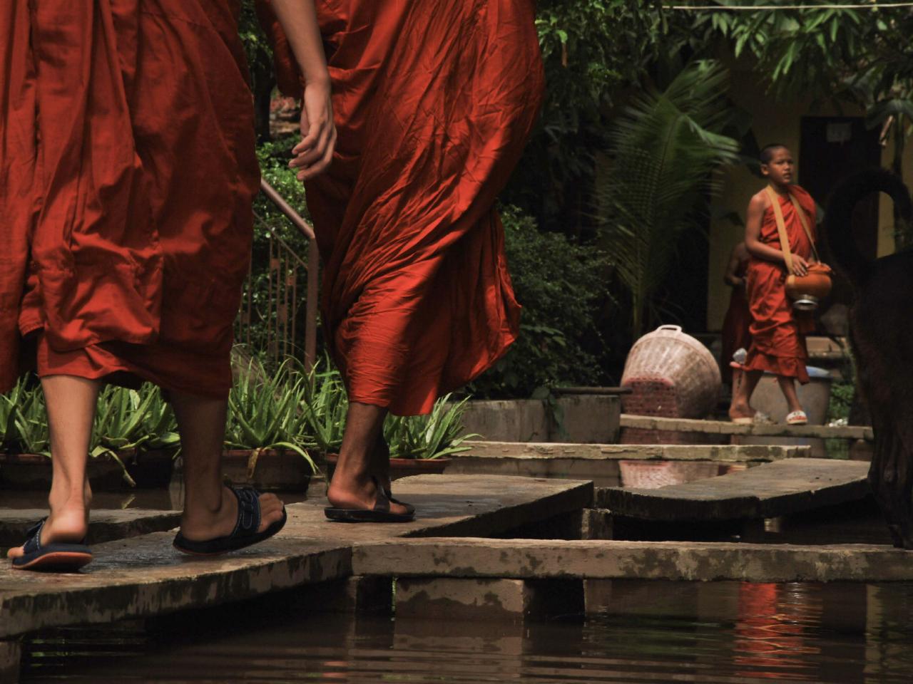 Buddhist monks walking in saffron robes near a pagoda